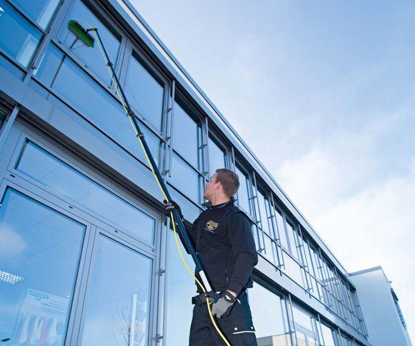 A professional OK Clean operative using a water-fed pole to clean the windows of a commercial building